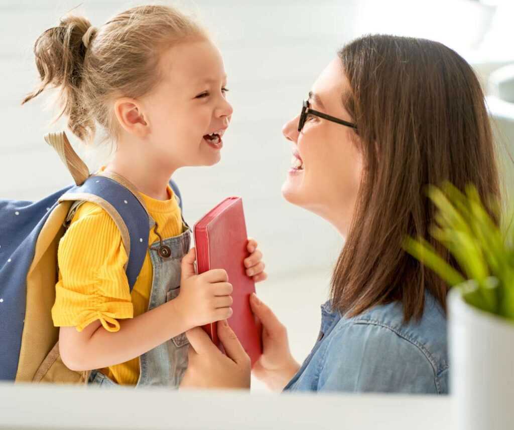 Mama uśmiecha się do dziecka gotowego iść do szkoły